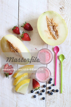 Fresh fruit and fruit yoghurt with spoons on a wooden surface