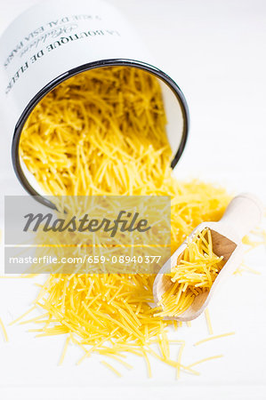 Angel hair pasta falling out of an overturned enamel bucket