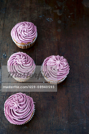 Four blueberry cupcakes on a dark wooden table