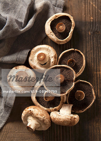 Nine mushrooms on a dark chopping board with a grey linen napkin