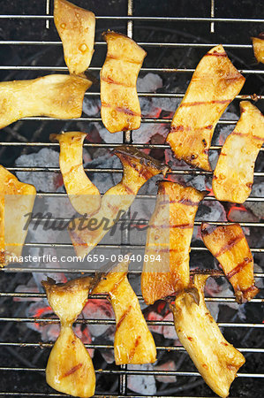 King trumpet mushrooms marinated in soy sauce and garlic on a barbecue