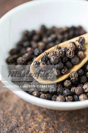 A bowl of black peppercorns (close-up)