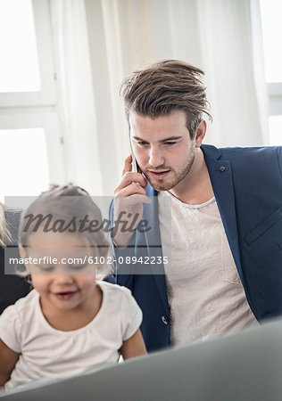 Mid adult man using phone, girl looking down