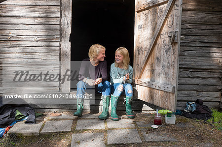 Girl and teenage boy sitting in front of barn