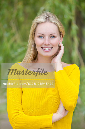 Portrait of a blonde woman in park smiling at camera