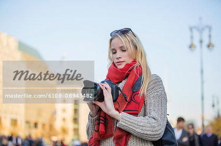 Pretty blonde woman with digital camera taking photos in a city in Europe