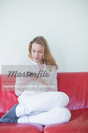 Pretty blonde woman with mobile on the couch