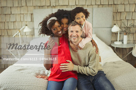 Portrait enthusiastic pregnant young family hugging on bed