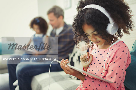 Girl with headphones using digital tablet on sofa