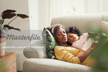 Serene mother and daughter napping and cuddling on sofa