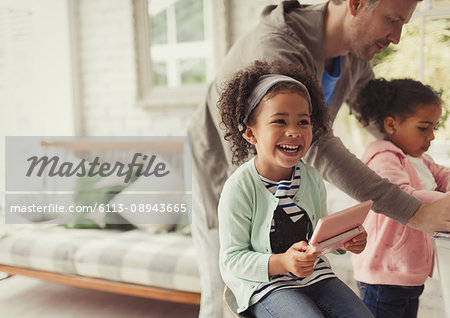 Laughing girl using digital tablet in living room