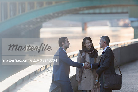 Businessmen handshaking at urban waterfront