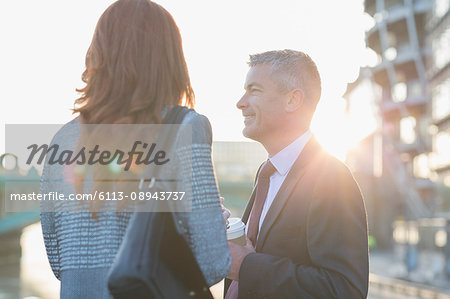 Businessman and businesswoman drinking coffee and talking outdoors