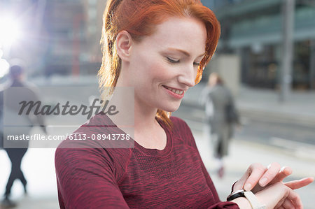 Close up smiling female runner checking smart watch