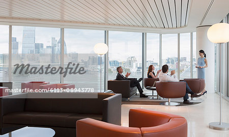 Business people clapping for businesswoman leading meeting in highrise urban lounge