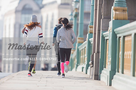 Runners running on sunny urban sidewalk