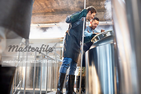 Male brewers checking vat in brewery