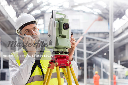 Male engineer using walkie-talkie and theodolite at construction site Male engineer using walkie-talkie and theodolite at construction site