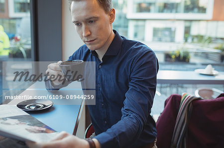 Male executive reading newspaper while having coffee in cafeteria