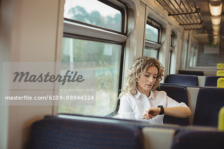 Woman checking time on her watch while travelling in train