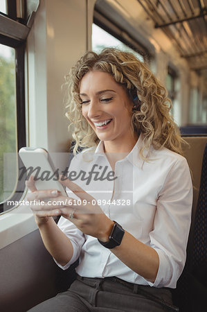 Smiling woman using mobile phone inside train compartment