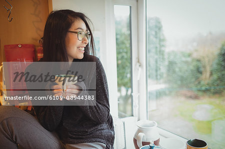 Smiling woman holding a coffee cup in kitchen at home