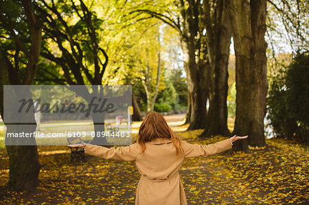 Rear view of woman standing in the park with arms wide open