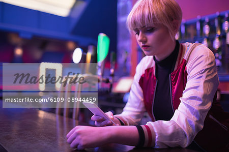 Female bartender using mobile phone at counter in bar