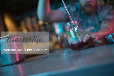 Bartender preparing cocktail at counter in bar