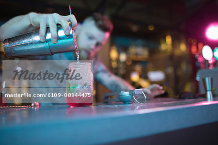 Bartender preparing cocktail at counter in bar