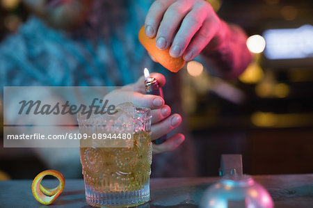Bartender preparing a flaming cocktail at counter in bar