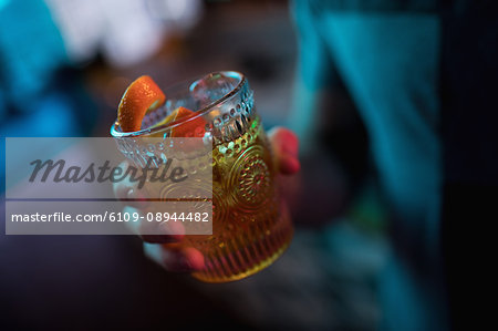 Man holding a glass of orange cocktail in bar