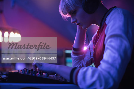 Female dj listening to headphones while playing music in bar Female dj listening to headphones while playing music in bar