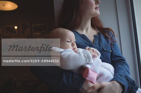 Mother holding her cute baby in arms at café