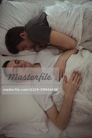 High angle view of gay couple sleeping together on the bed