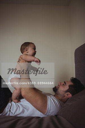 Father playing with his baby in bedroom at home