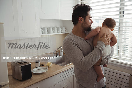 Father comforting his baby while standing in kitchen