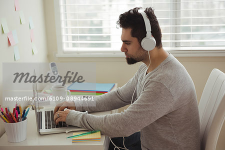 Side view of man using laptop while sitting at desk