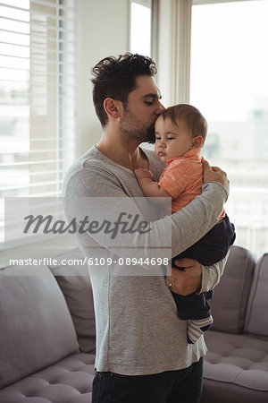 Father kissing his baby in living room at home