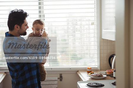 Father and his baby using mobile phone in kitchen
