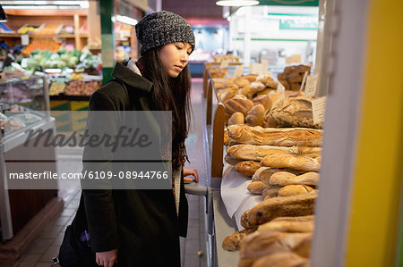 Woman looking at various breads at the bakery counter in the supermarket