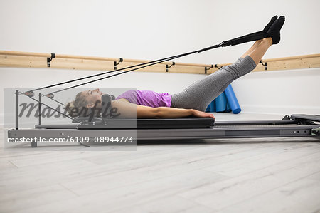 Woman exercising on reformer in gym