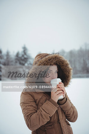 Beautiful woman in fur jacket having coffee during winter