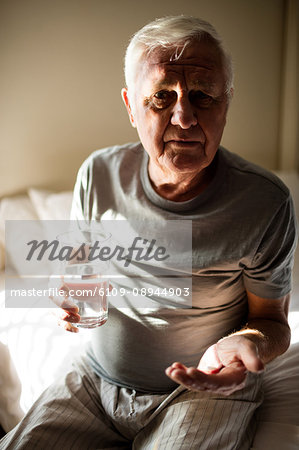 Senior man taking medicine in the bedroom at home