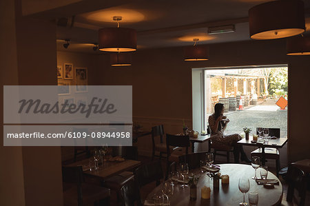 Thoughtful woman having cup of coffee near window at café