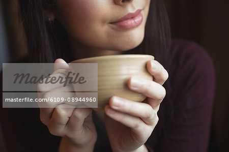 Thoughtful woman having cup of coffee at café