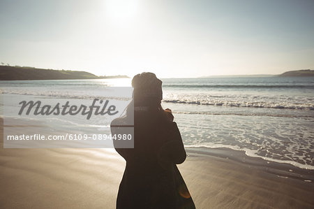 Rear view of woman standing on beach during day