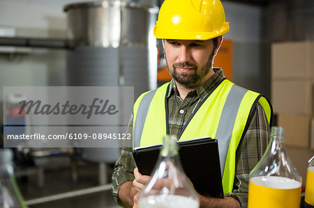 Thoughtful male worker using digital tablet in juice factory