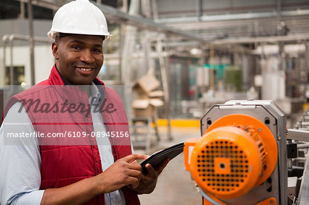 Happy male employee using digital tablet in juice factory