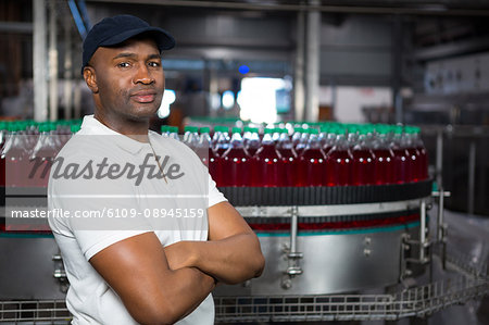 Portrait of confident male employee with arms crossed standing in factory